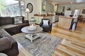 A living room with a sofa, armchair, coffee table, and a rug.