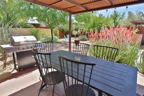 An outdoor patio with a grill, a table, and chairs.