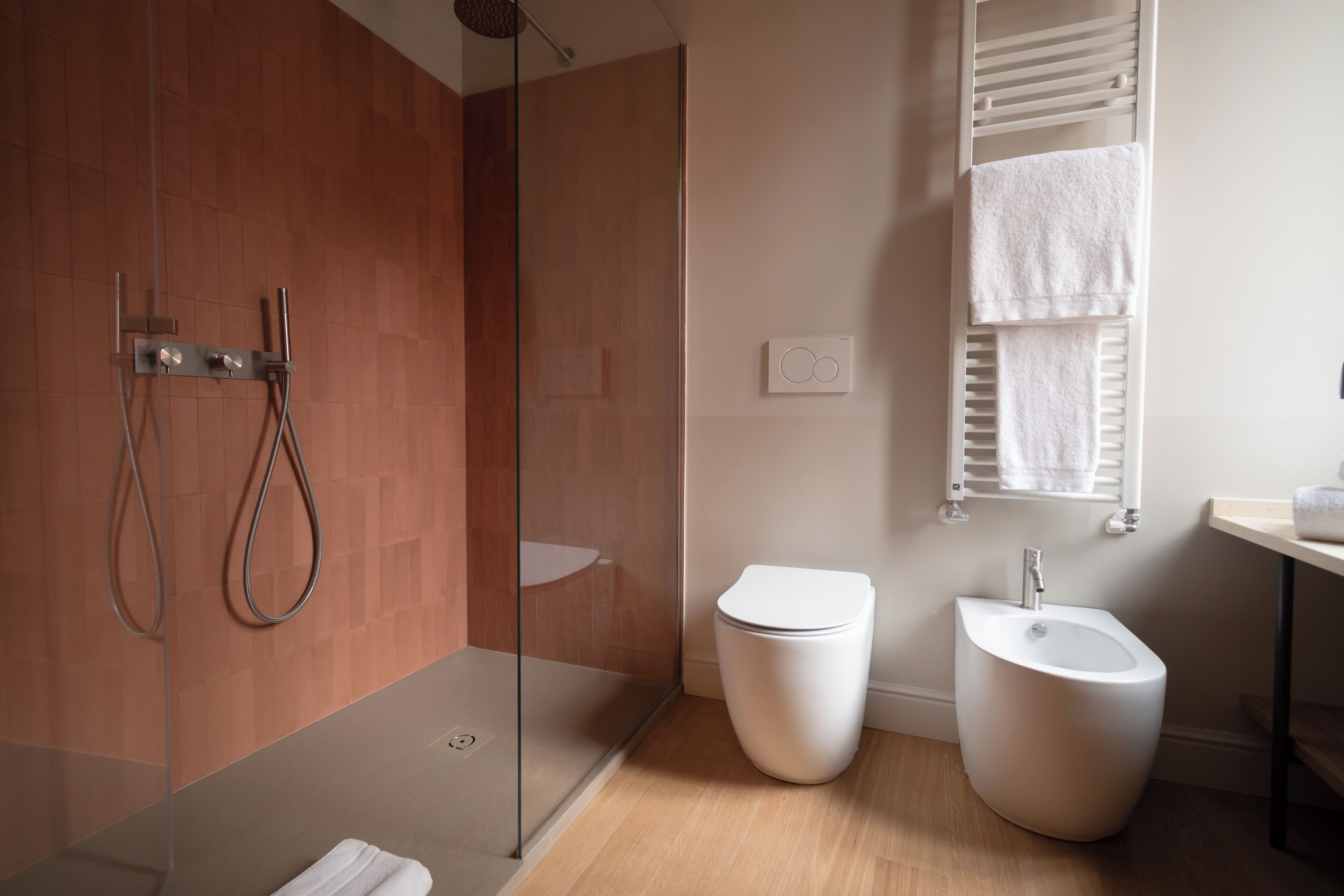 A modern bathroom with a glass-enclosed shower, a white toilet, and a bidet.