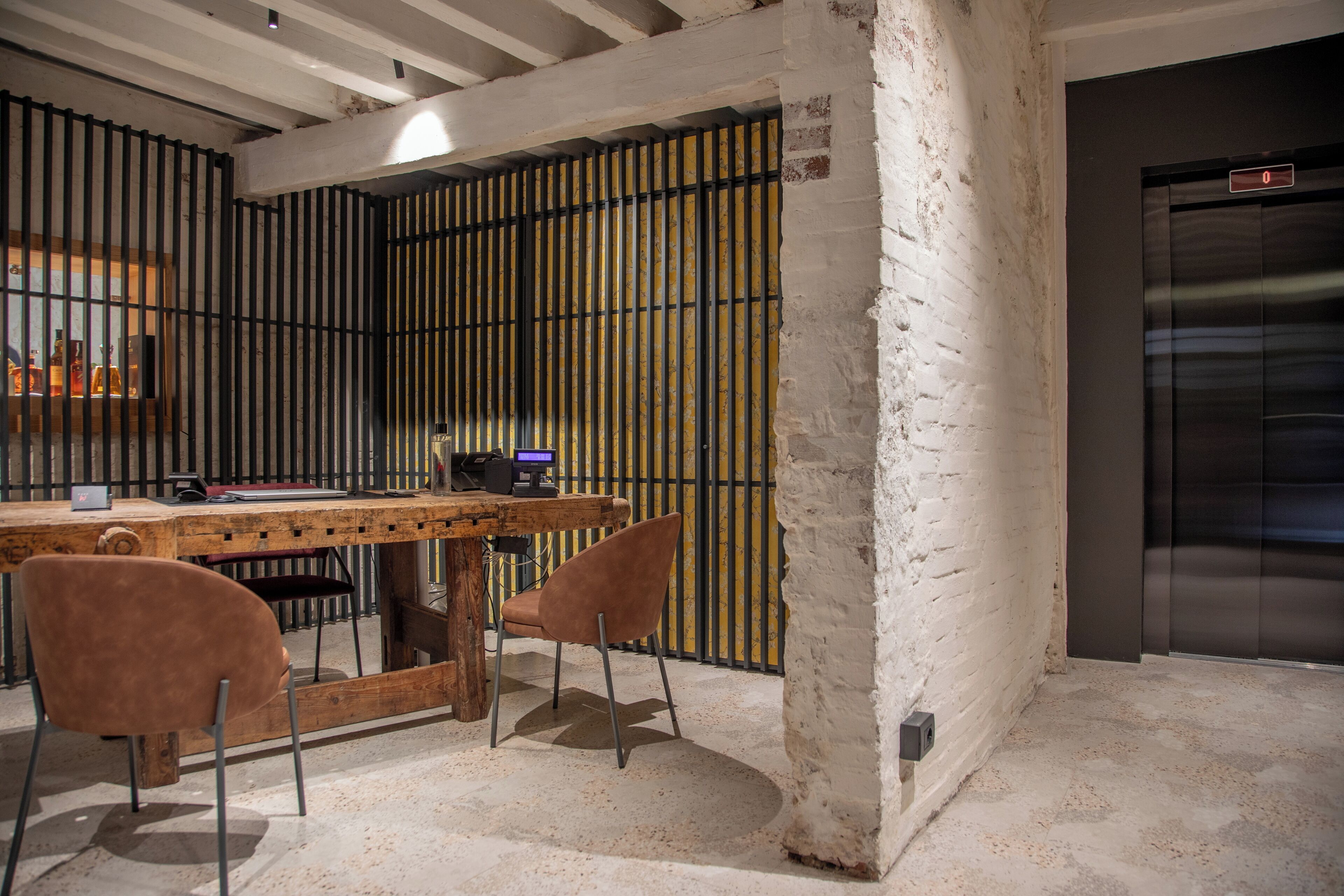 A modern interior with a wooden desk, two chairs, and a metal partition.