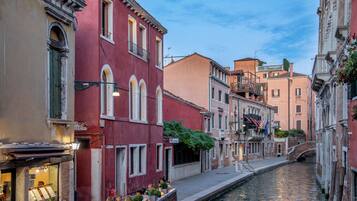 A canal-side street with buildings, a bridge, and a restaurant with outdoor seating.