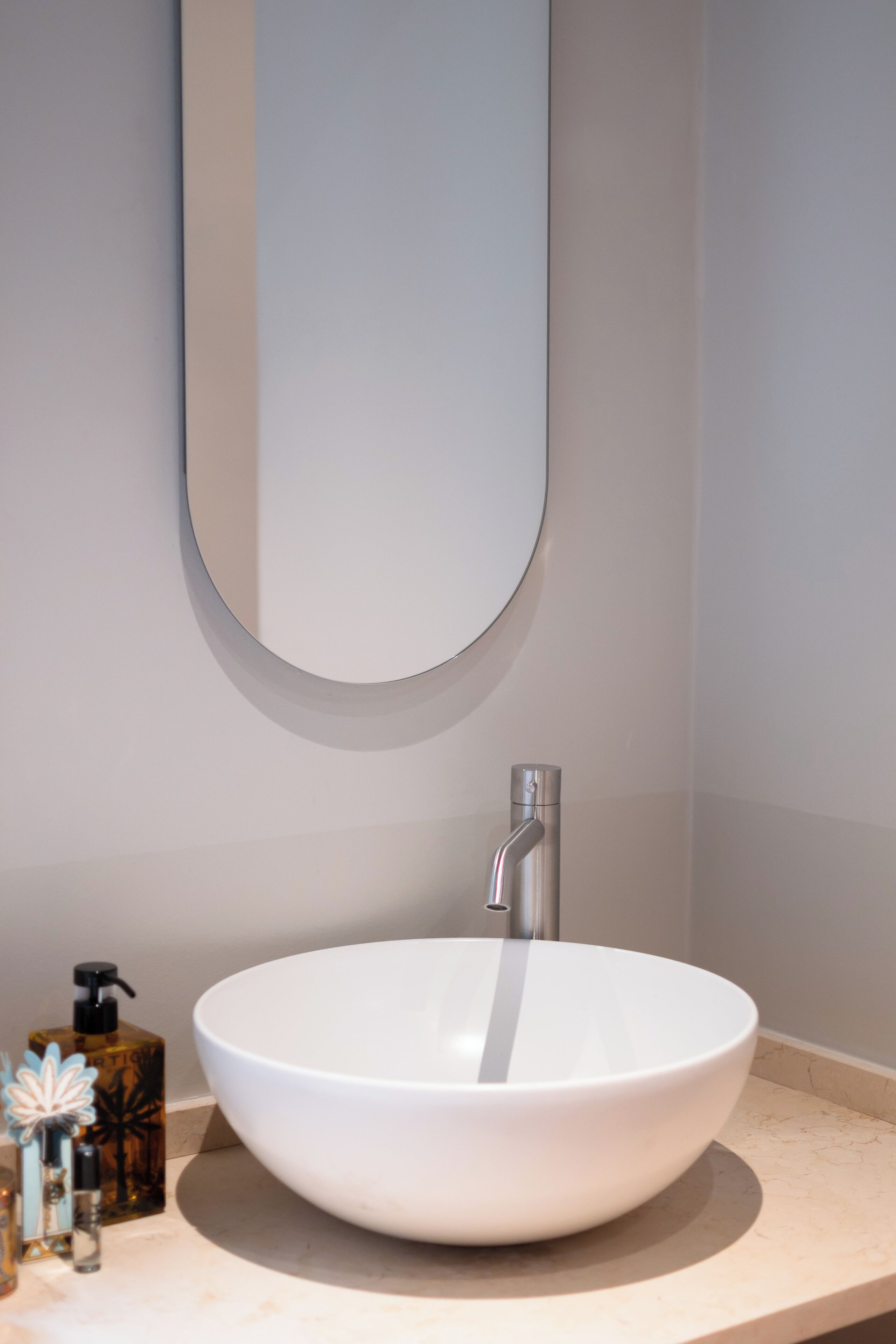 A modern bathroom with a white vessel sink, a round mirror, and a faucet.
