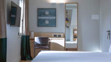 Habitación de hotel con cama, escritorio, silla, televisor y una obra de arte enmarcada en la pared.