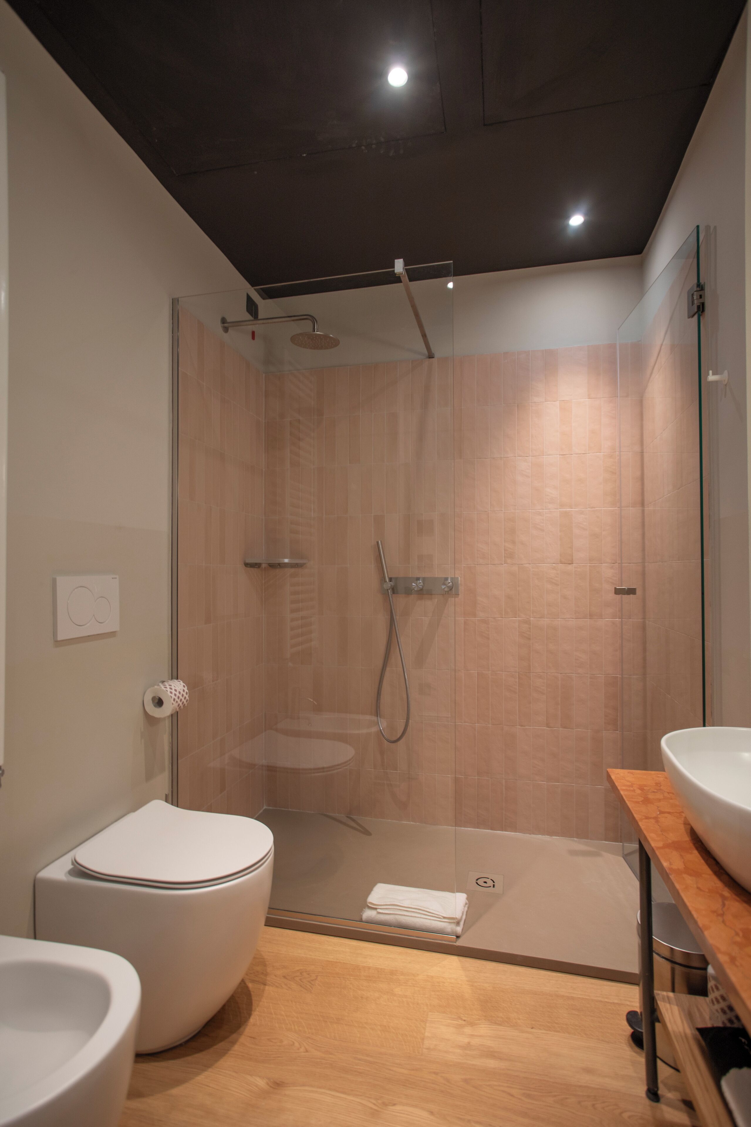 Une salle de bain moderne dotée d’une douche à parois de verre, de toilettes et d’un lavabo.