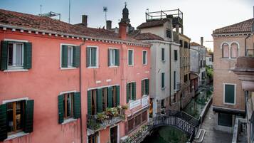 Un canal étroit dans une ville européenne historique, bordé de bâtiments à l’architecture traditionnelle et aux volets verts.