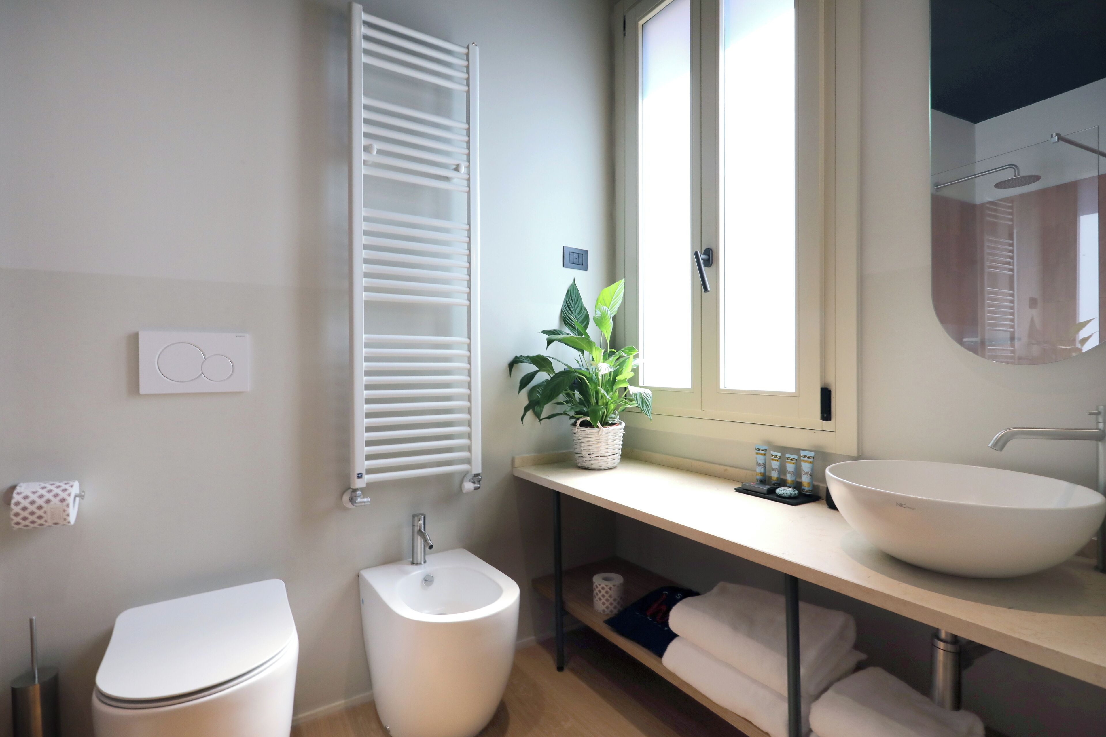 Ein modernes Badezimmer mit Toilette, Bidet und einem großen Waschbecken mit Spiegel darüber.