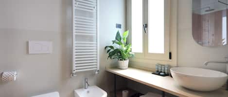 Ein modernes Badezimmer mit Toilette, Bidet und einem großen Waschbecken mit Spiegel darüber.