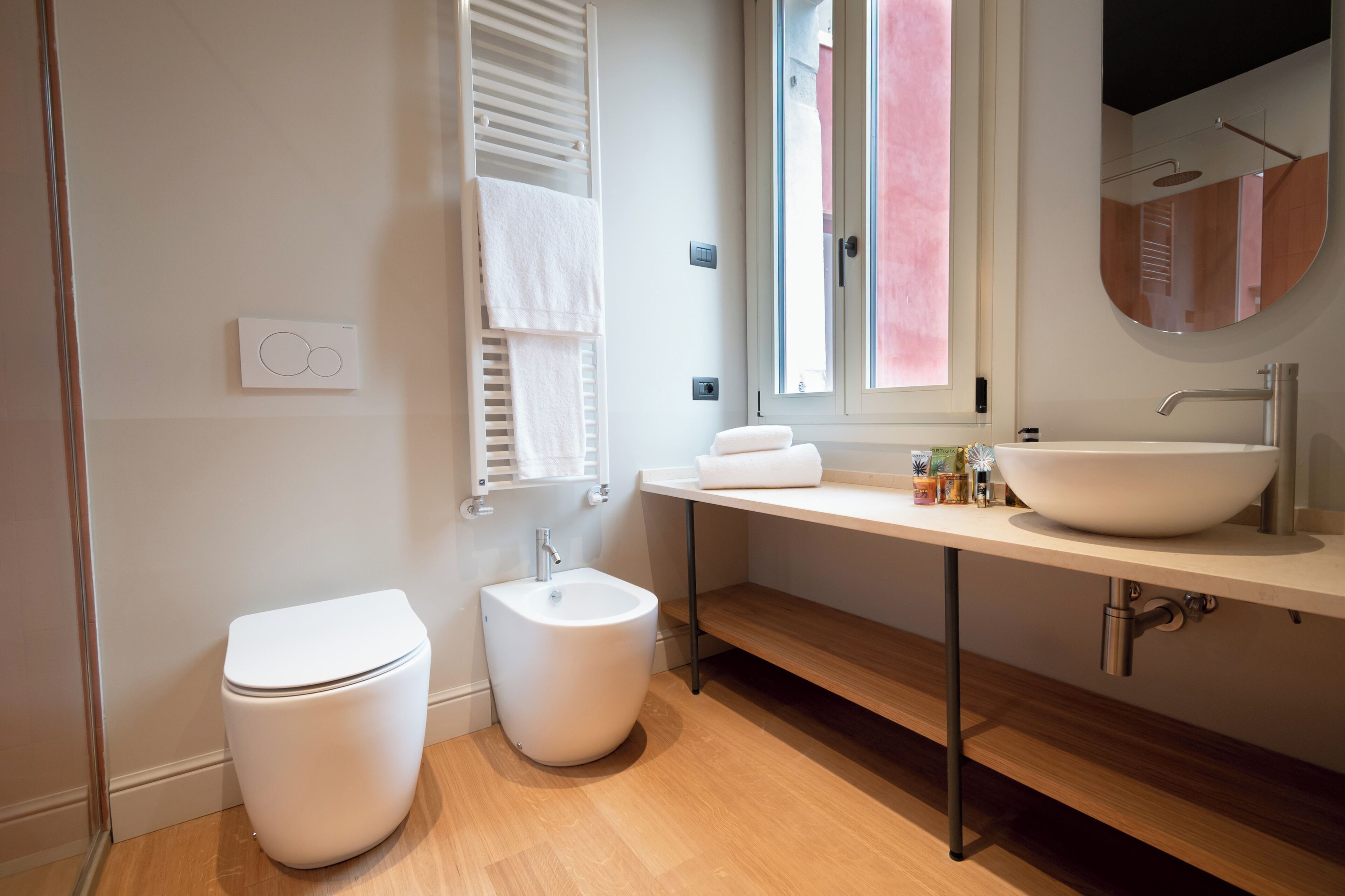 A modern bathroom with a toilet, bidet, vanity with a sink, and a mirror.