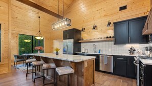 A modern kitchen with a wooden interior, stainless steel appliances, and a large island with bar stools.