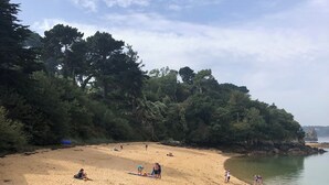 Una platja sorrenca amb gent relaxant i una barca petita al primer pla.