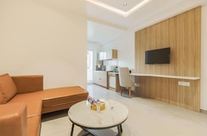 A modern living room with a sofa, a round coffee table, and a TV mounted on a wooden wall.