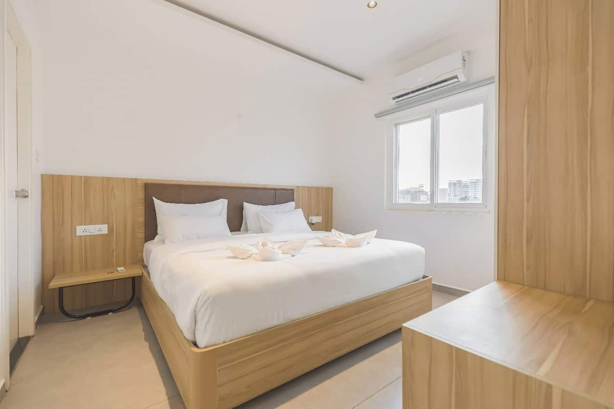 A modern hotel room with a wooden bed, a bedside table, and a window with a city view.