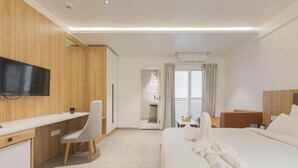 A hotel room with a bed, a desk, a chair, a television, and a balcony with curtains. - Akoya Business Hotel - Smart Stays, Whitefield (Bengaluru)