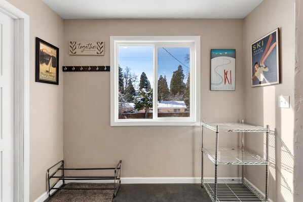 A hallway with a window, a metal rack, and a framed picture on the wall.