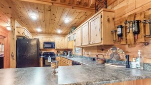 A kitchen with wooden cabinets, granite countertops, a refrigerator, microwave, and a stove.
