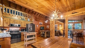A rustic wooden cabin interior with a kitchen, dining area, and a large window overlooking the forest. - Wine Knot in Blue Ridge (Blue Ridge)