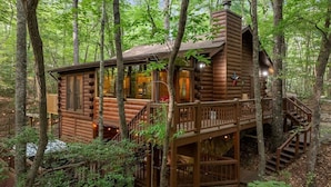 A log cabin with a balcony and a staircase leading to a deck, surrounded by trees. - Wine Knot in Blue Ridge (Blue Ridge)