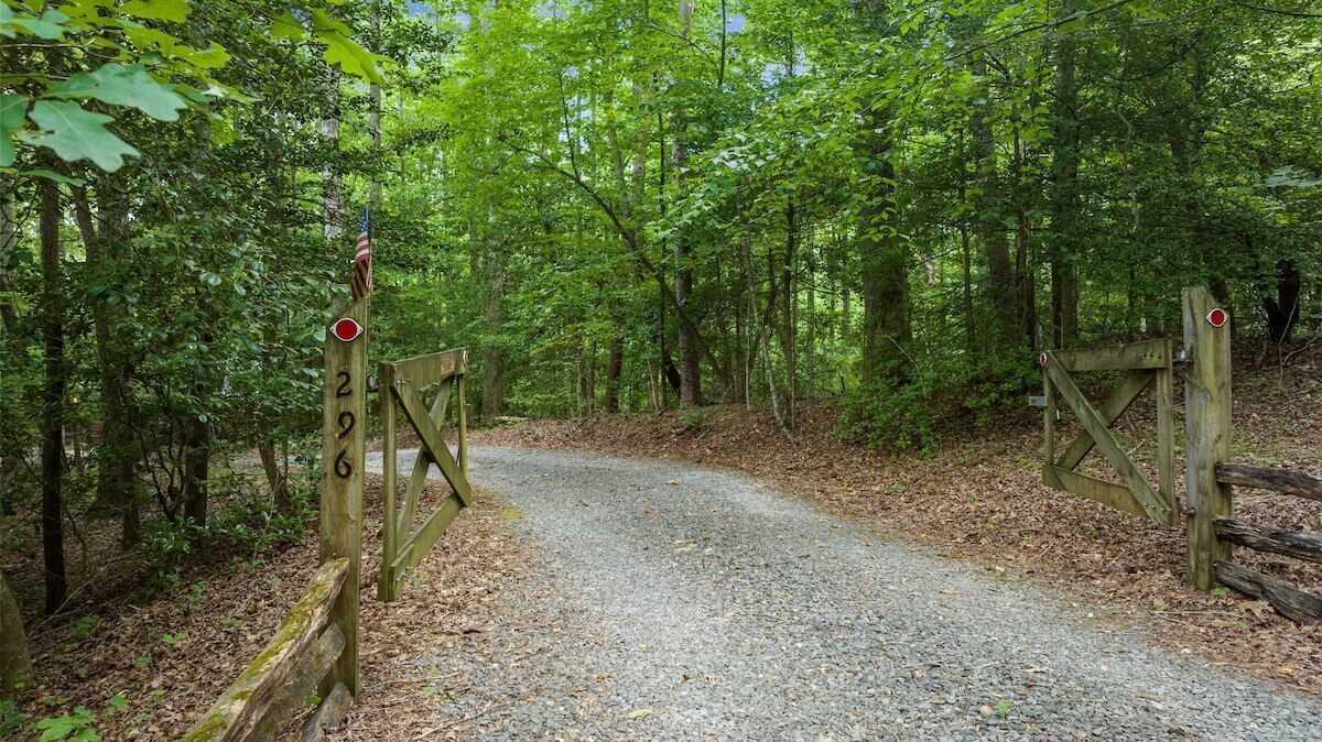 A gravel path leading through a wooded area with wooden gates and a signpost.