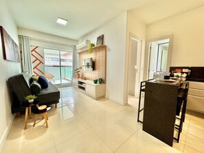 Sala de estar com sofa preto, janela ampla e vista para cidade