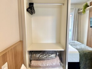 Banheiro com box de vidro branco, pia e toalha de banho pendurada