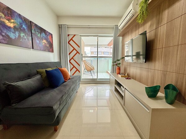 Sala ampla com sofa cinza, Smart TV e janela grande