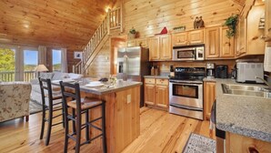 A wooden cabin interior with a kitchen, dining area, and a staircase. - Cardinal and Bear Lodge (Blue Ridge)