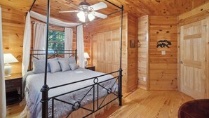 A wooden cabin bedroom with a four-poster bed, a ceiling fan, and a bear mural on the wall. - Cardinal and Bear Lodge (Blue Ridge)