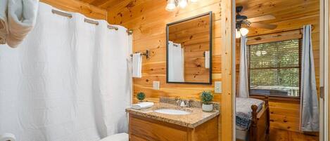 A wooden cabin bathroom with a wooden vanity, a mirror, a sink, and a toilet.