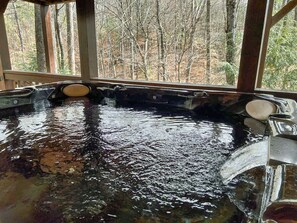 Jacuzzi amb terrassa de fusta i vista a un bosc.