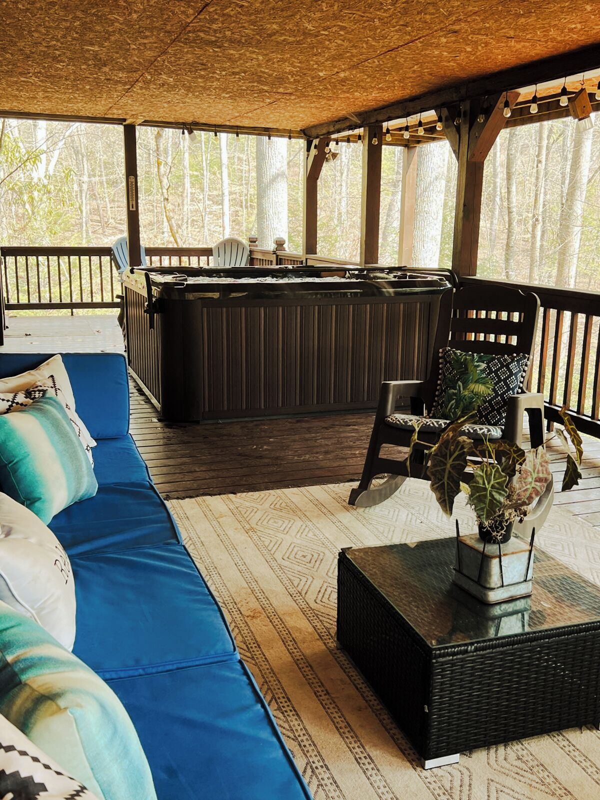 A covered outdoor seating area with a sofa, chairs, and a bar.