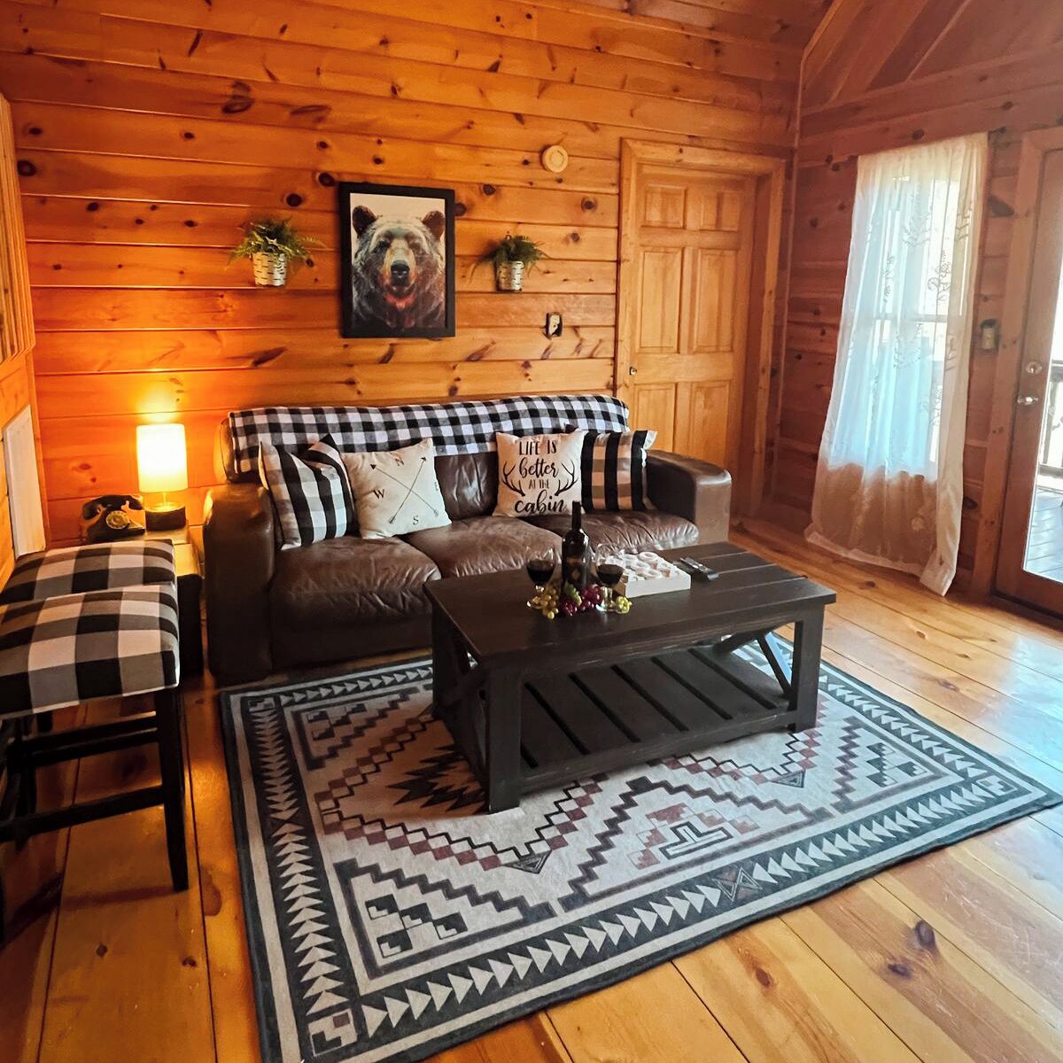 Una habitación acogedora de estilo cabaña, con un sofá estampado de cuadros, una mesa de centro y una alfombra con diseño.