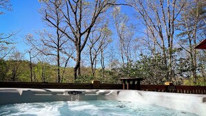 A hot tub area with a clear blue sky and trees in the background. - Bigfoot's Hideaway | Hot Tub | Fire Pit | Cozy Wooded Retreat (Blue Ridge)