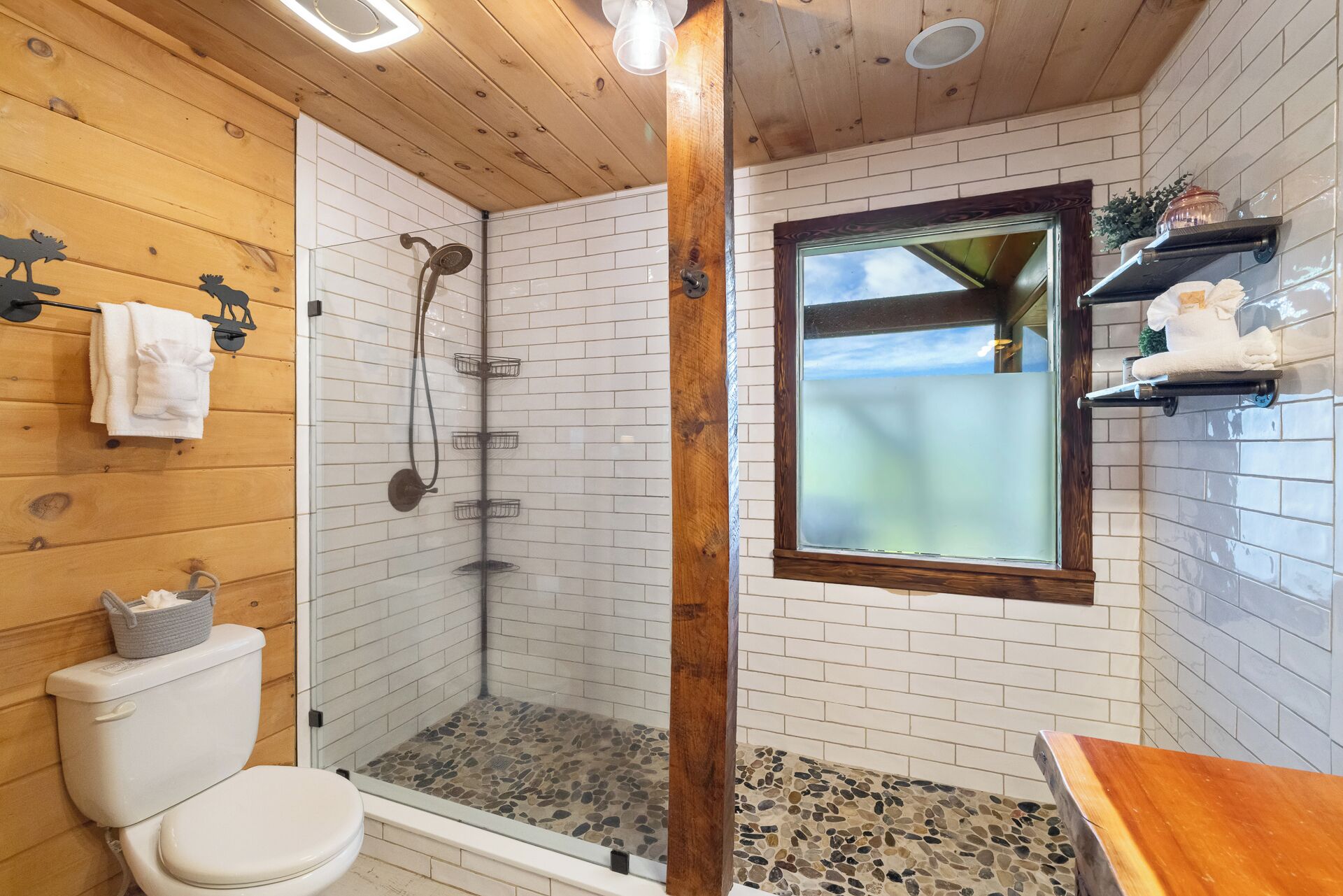 A bathroom with a shower, toilet, and a window.