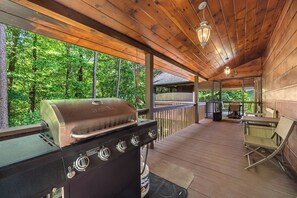 Un espacio al aire libre techado con una parrilla, una mesa y sillas.