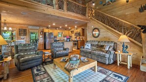 Interior acogedor de una cabaña con comedor, cocina y una escalera que conduce a un nivel superior.