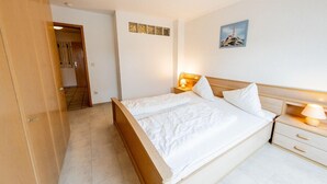 Een slaapkamer met een houten bed, nachtkastjes met lampen, een kledingkast en een schilderij aan de muur.