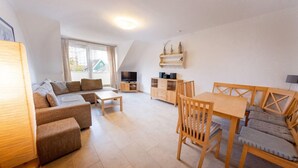 Een moderne woonkamer met een bank, een eettafel en een televisie.