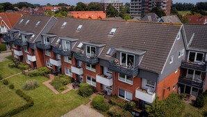 Een rij moderne appartementencomplexen met balkons, waarvan sommige buitenmeubels en beplanting hebben.