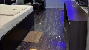 Ein modernes Hotelzimmer mit Bett, Schreibtisch, Sitzecke und Dusche.