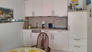 A compact kitchen with white cabinets, a coffee maker, and a small countertop. - Central vacation apartment Norderney (Norderney)