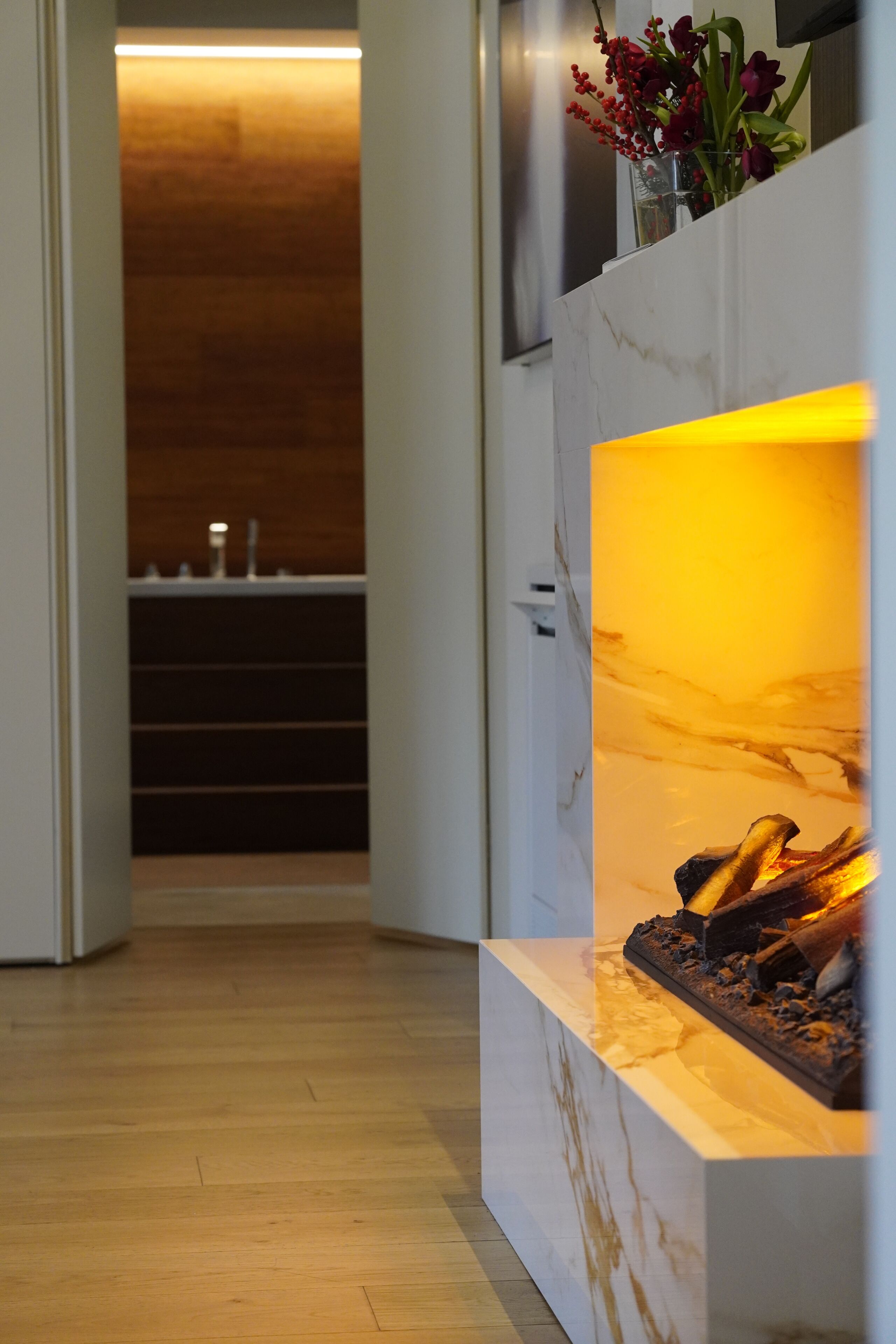 Un interno moderno con camino in marmo, pavimento in legno e parete di legno sullo sfondo.