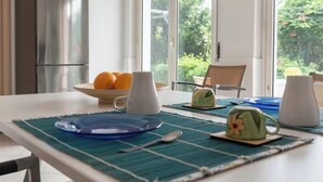 A dining table set with blue plates, a white mug, and a green cup with a flower design. - Terrace Garden Apartment (Aci Trezza)