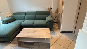 A living room with a green sofa, a wooden coffee table, and a tiled floor. - Terrace Garden Apartment (Aci Trezza)