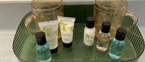 Een glazen dienblad met diverse persoonlijke verzorgingsproducten, zoals shampoos en conditioners, op een aanrecht.
