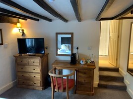 A cozy room with a wooden desk, a television, and a chair.