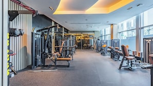 Een sportschool met diverse fitnessapparaten, een halterrek en een spiegel.