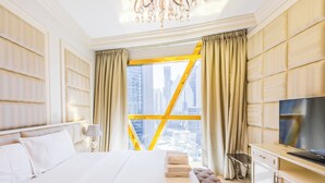 Een moderne hotelkamer met een groot bed, een televisie en een stadsgezicht door een raam met gele omlijsting.