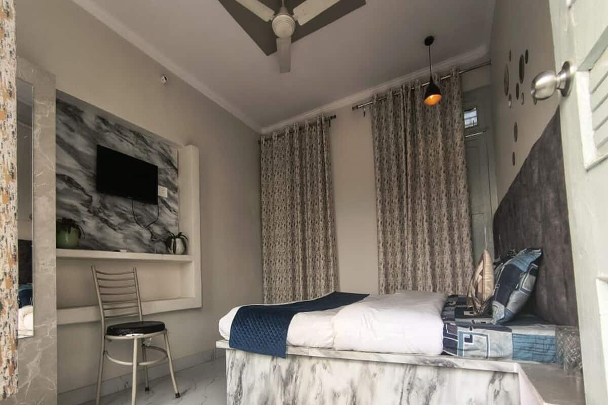 Una camera da letto con un letto, una sedia, un ventilatore a soffitto e tende.