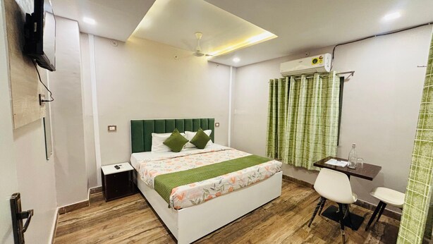 Ein modernes Hotelzimmer mit Bett, Nachttisch, Schreibtisch, Stuhl und einem an der Wand befestigten Flachbildfernseher.