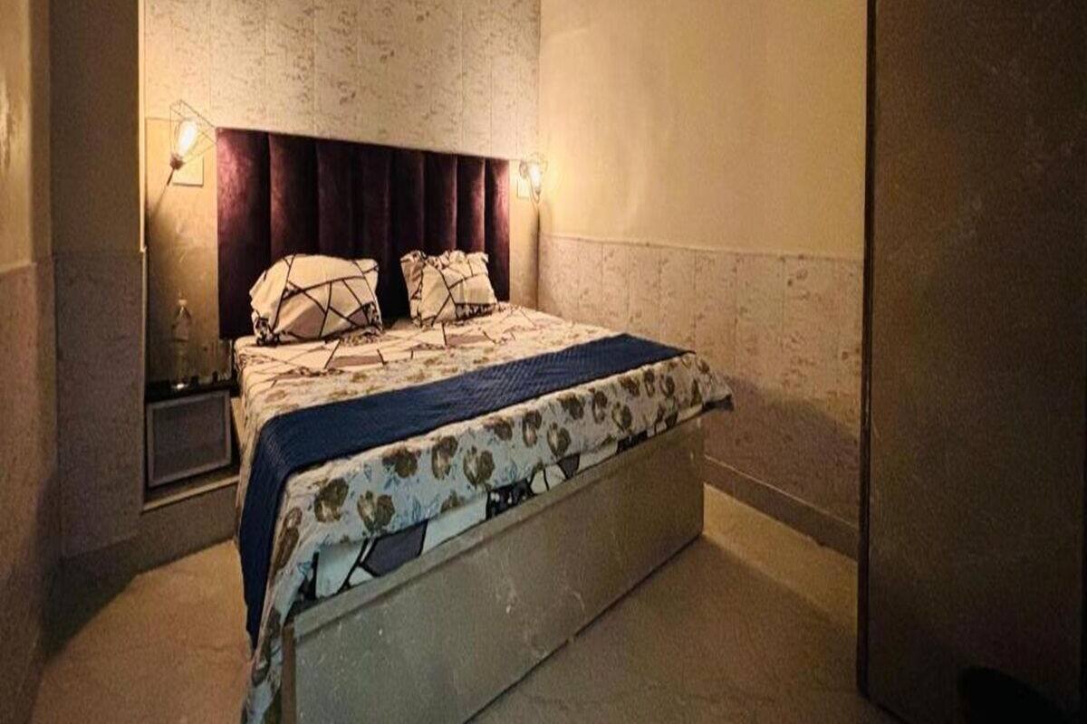 Una camera da letto moderna con un letto, un comodino e una lampada a parete.